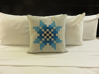 Blue pixelated star decorative pillow on white bed