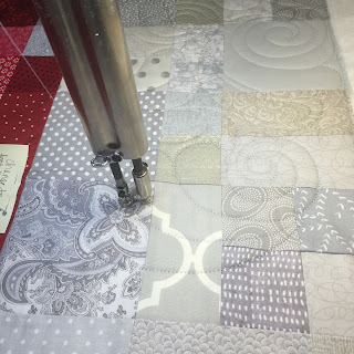 Longarm quilting machine stitching gray patchwork quilt