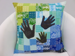 Patchwork pillow with three black handprints
