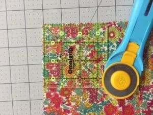 A pair of scissors and a quilt on the cutting mat.