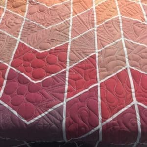 A close up of the quilted fabric on a bed.