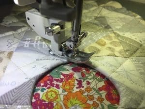 A sewing machine is cutting fabric with flowers on it.