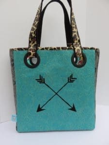A turquoise bag with leopard print handles and an arrow design.