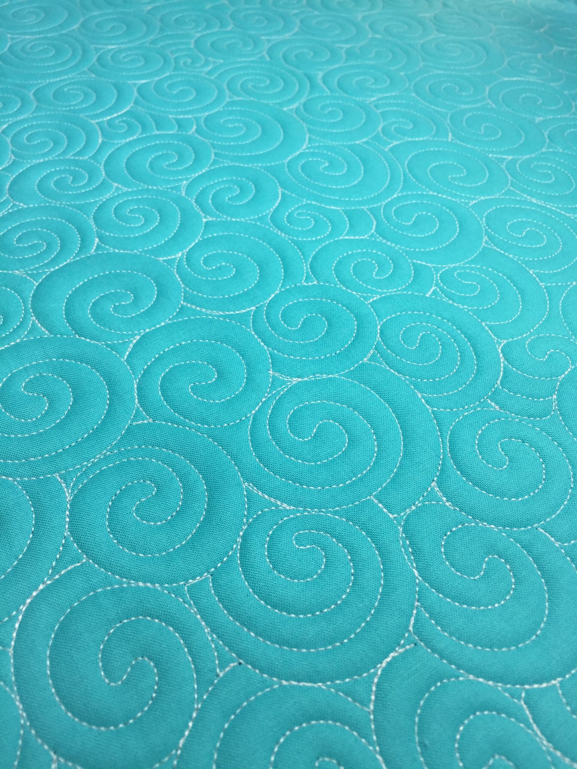 Turquoise quilted fabric with stitched spiral pattern