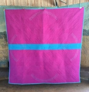 A pink and blue blanket sitting on top of a wooden floor.