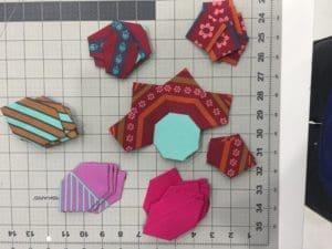 A close up of some fabric pieces on a cutting mat