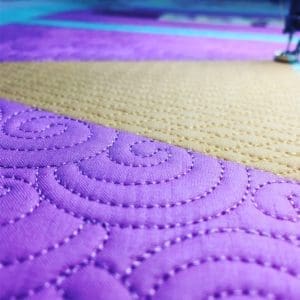 A close up of the quilting on a purple quilt