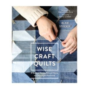 A book cover with two hands holding up a quilt.