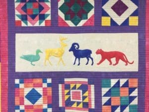 A quilt with animals and birds on it.