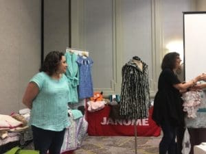 Two women standing in front of a table with clothes on it.