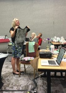A woman holding up an item in front of two other people.