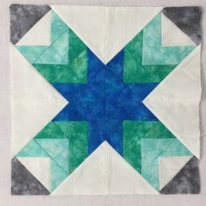 A quilt block with an x in the center.