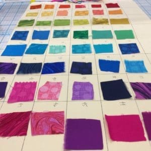 A tile floor with many different colored squares of fabric.