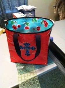 A red bag with cherries on it sitting on top of a table.