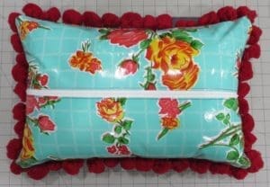 A pillow with red flowers and blue squares on it