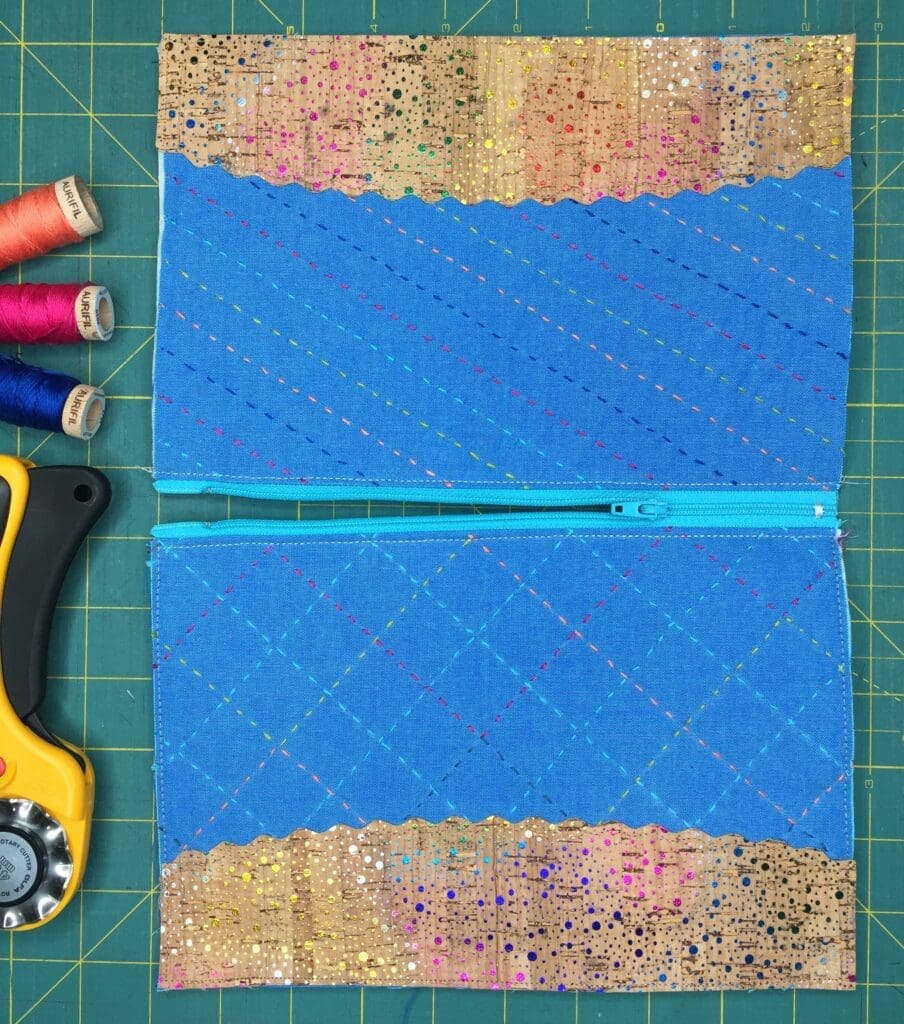 A pair of zippers and sewing supplies on top of a green cutting mat.