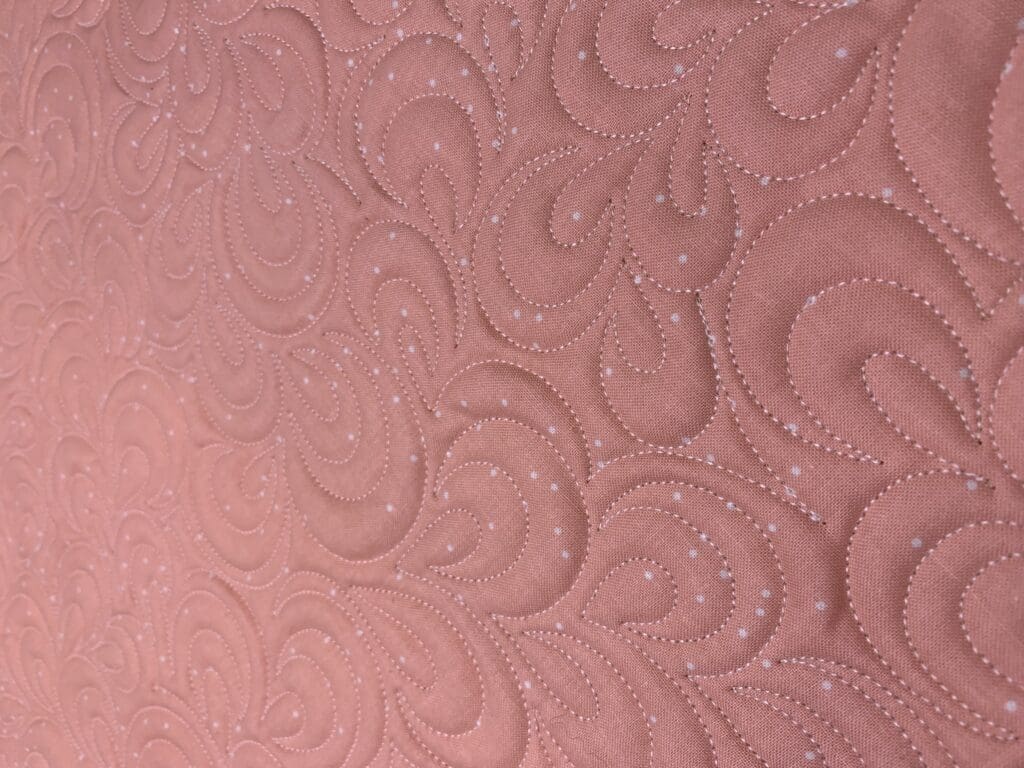 A close up of the pink fabric with swirls