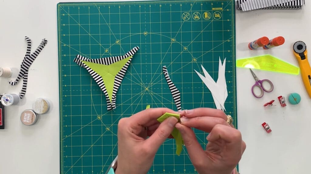 A person is sewing the fabric on a bikini top.