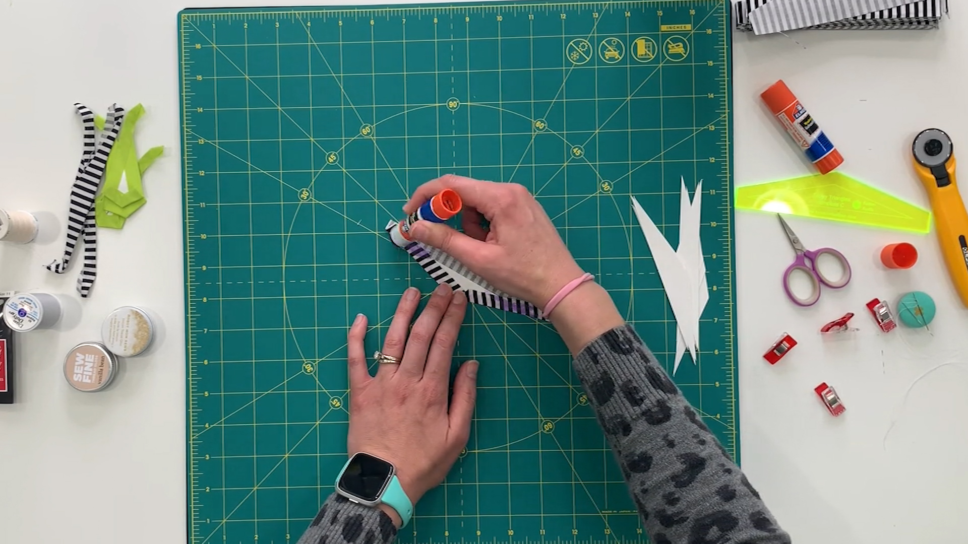 A person using a pair of scissors on a cutting mat.
