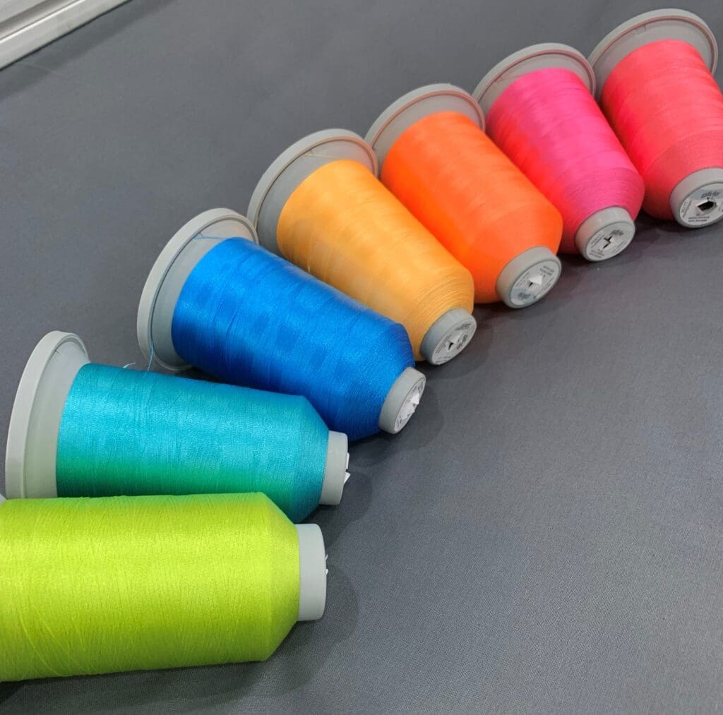 A row of different colored thread spools on top of a table.