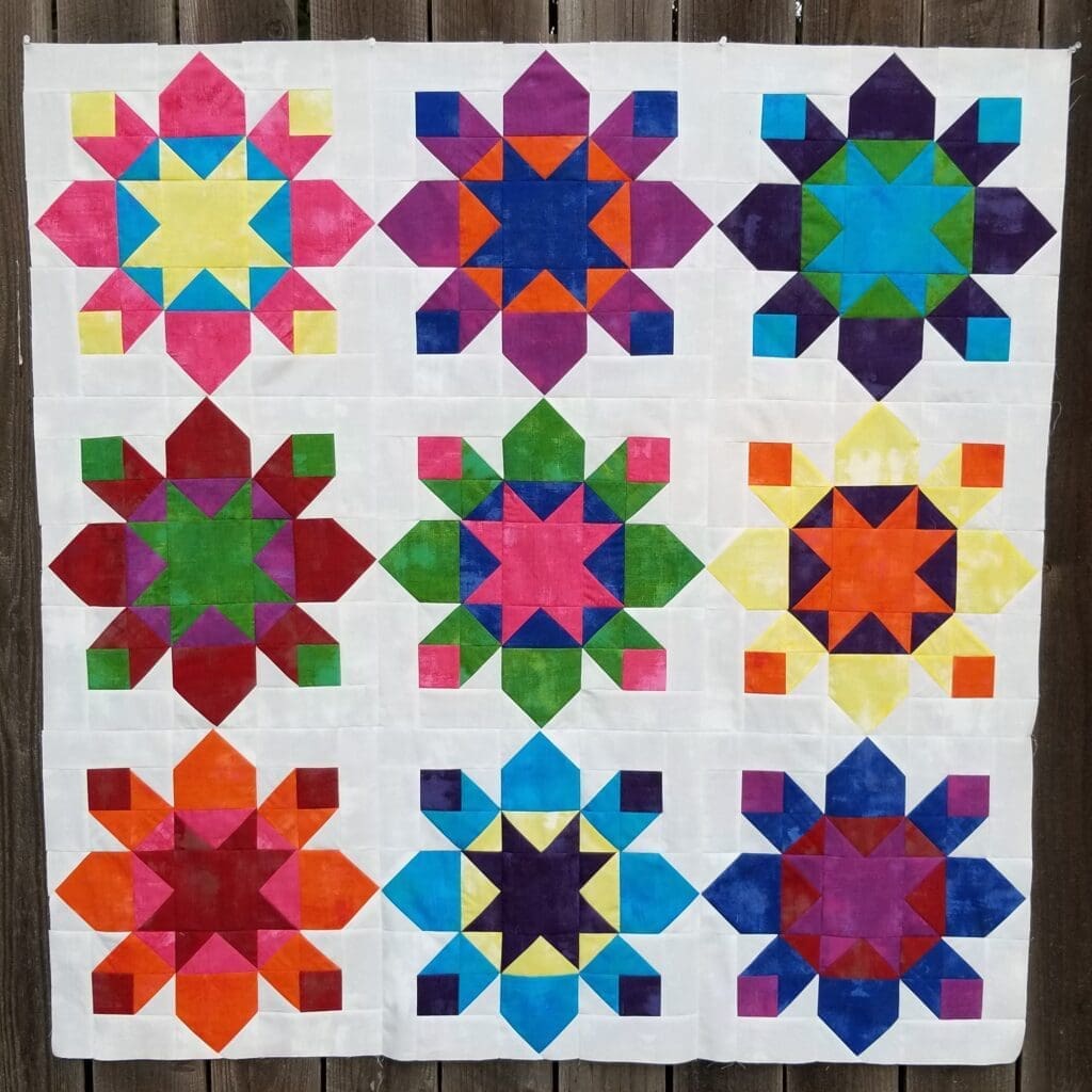 A quilt with nine different colored stars on it.