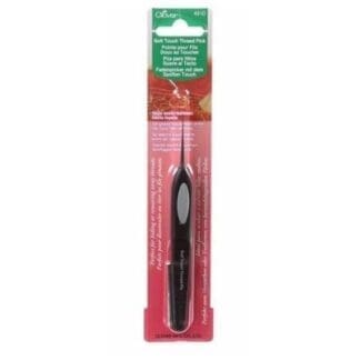 A black toothbrush in its package on top of a white table.