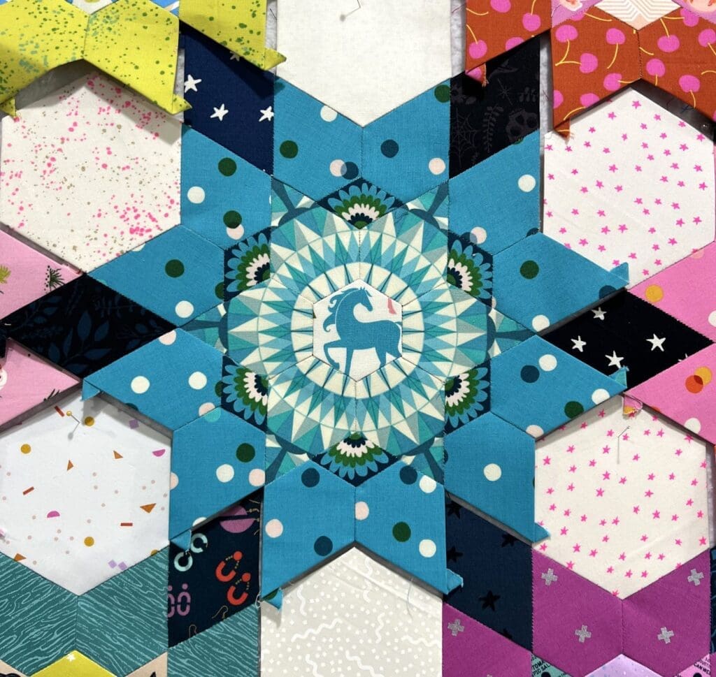 Intricate star-shaped rangoli design with yellow and purple hues.