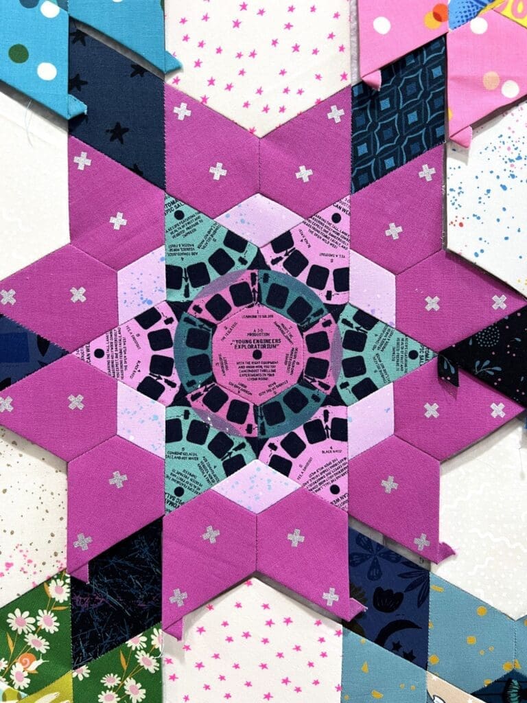 Intricate star-shaped rangoli design with yellow and purple hues.