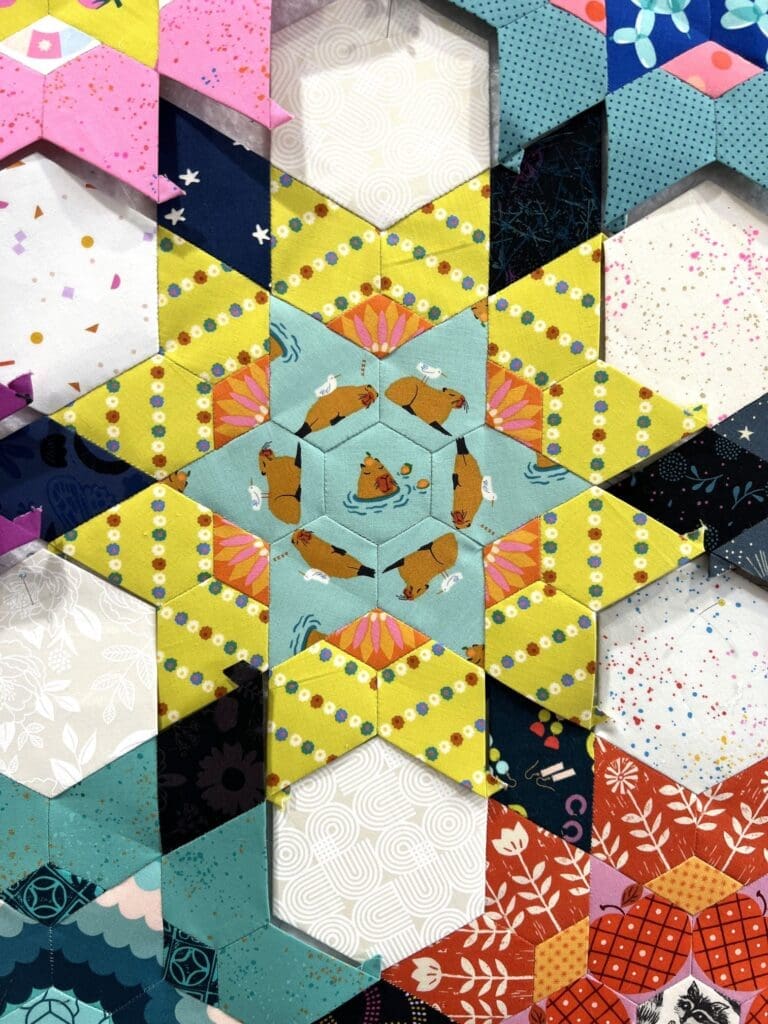 Intricate star-shaped rangoli design with yellow and purple hues.