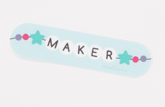 White beads spelling 'MAKER' with star-shaped beads on a blue strip.