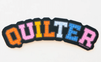 Colorful embroidered word 'QUILTER' on black fabric.